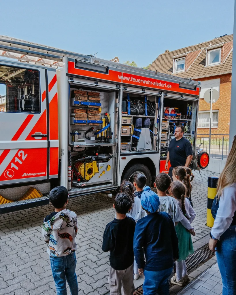 Feuerwehrmann zeigt Kita-Kindern die Ausrüstung des Feuerwehrfahrzeugs
