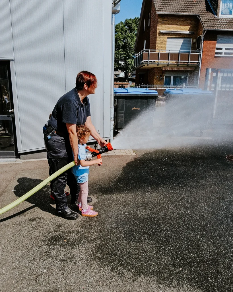 Ein Kind hält den Feuerwehrschlauch beim Besuch bei der Feuerwehr Alsdorf