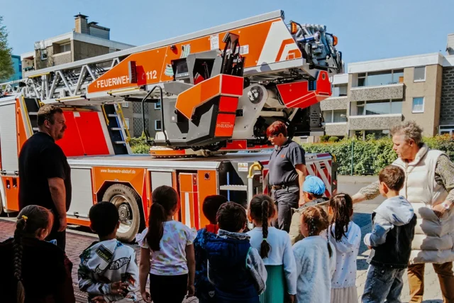 Ein Feuerwehrmann erklärt den Kindern die Ausrüstung bei der Feuerwehr Alsdorf