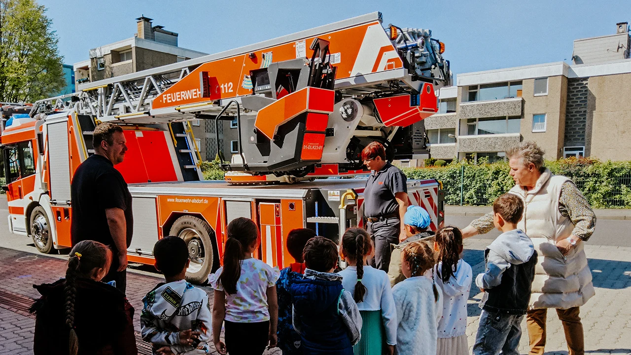 Ein Feuerwehrmann erklärt den Kindern die Ausrüstung bei der Feuerwehr Alsdorf